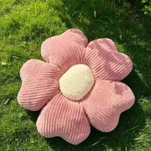 Roze Cuddle Puff jastuk u obliku cvetića od rebrastog pliša, sa krem sredinom, na travi